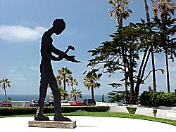 tall sculpture of worker, ocean behind